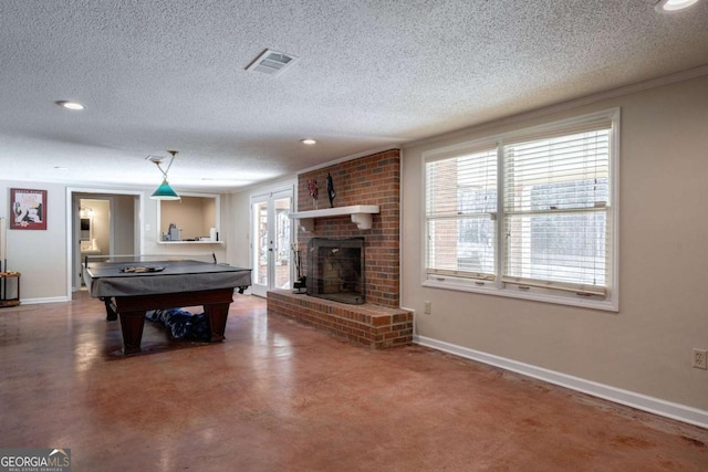 game room featuring a brick fireplace, ornamental molding, a textured ceiling, pool table, and concrete floors