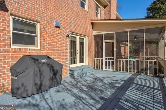 wooden deck with french doors, a grill, and a sunroom