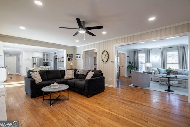 living room featuring crown molding, light hardwood / wood-style flooring, and ceiling fan