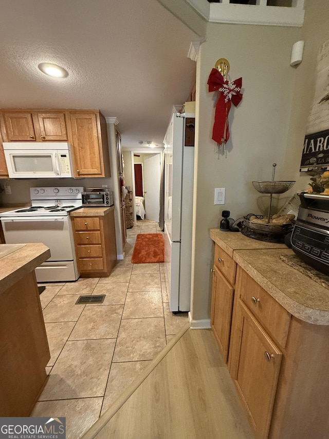 kitchen featuring white appliances, a textured ceiling, and light tile patterned floors