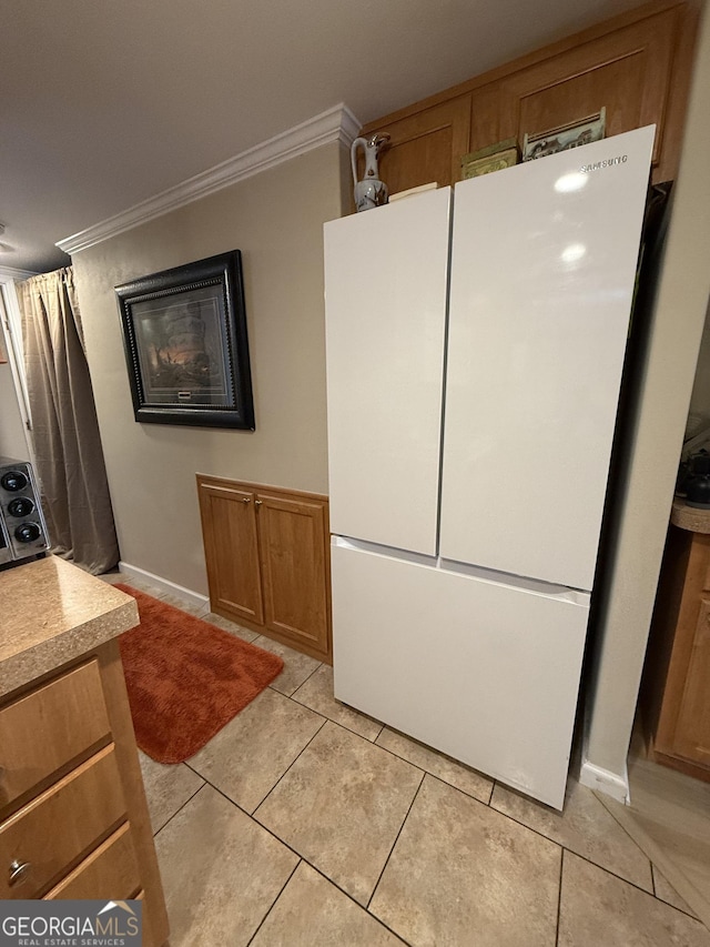 kitchen with light tile patterned flooring, crown molding, and white refrigerator