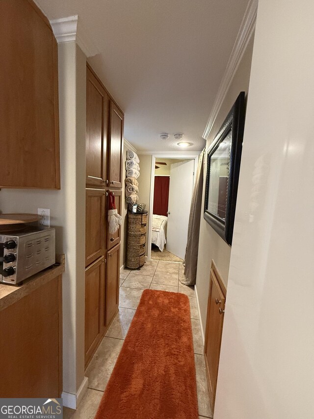 hallway with crown molding and light tile patterned floors