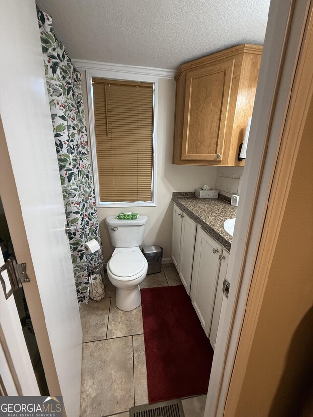 bathroom featuring tile patterned floors, vanity, a textured ceiling, and toilet