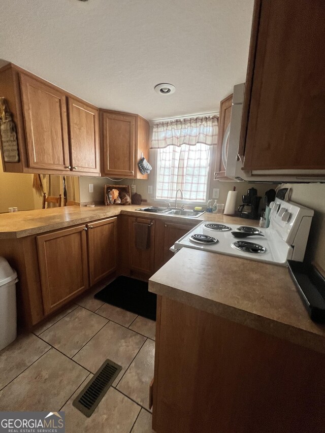 kitchen featuring white electric range oven, sink, and light tile patterned flooring