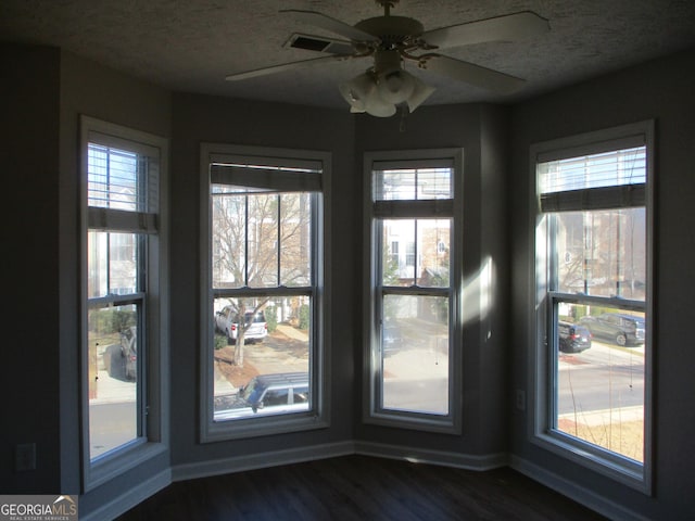 interior space with a textured ceiling, ceiling fan, and dark wood-type flooring