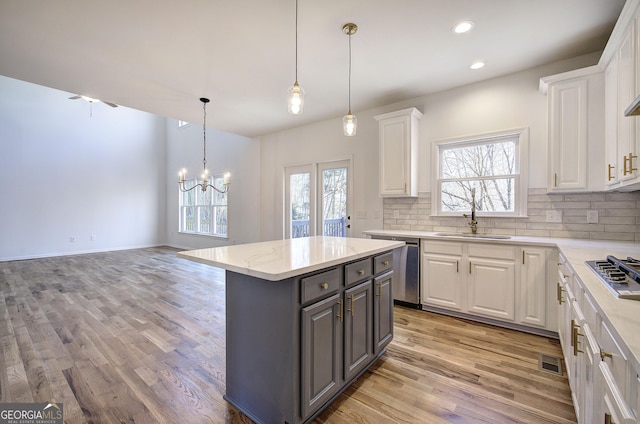 kitchen with decorative light fixtures, sink, a kitchen island, and white cabinetry