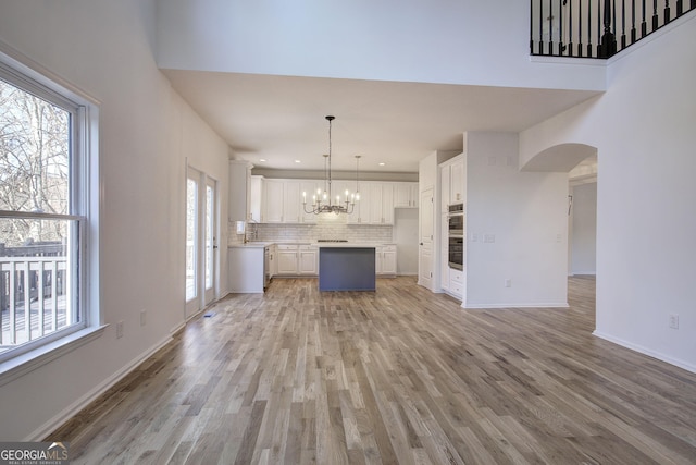 unfurnished living room with sink, light hardwood / wood-style flooring, and an inviting chandelier