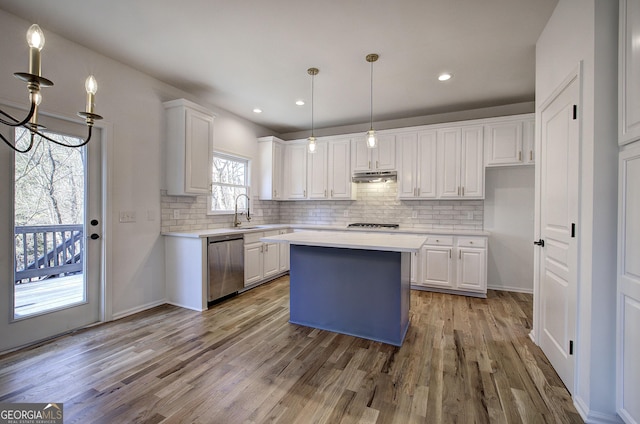 kitchen with stainless steel dishwasher, a kitchen island, white cabinets, and hanging light fixtures