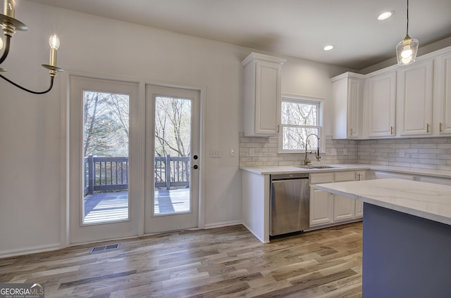 kitchen with stainless steel dishwasher, decorative backsplash, white cabinetry, and sink