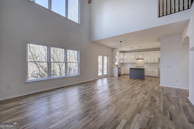 unfurnished living room featuring a high ceiling, a notable chandelier, and wood-type flooring