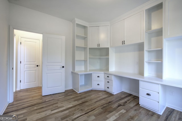 unfurnished office featuring built in desk and dark hardwood / wood-style floors