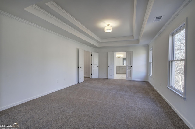 unfurnished bedroom featuring ensuite bathroom, a raised ceiling, ornamental molding, and carpet flooring