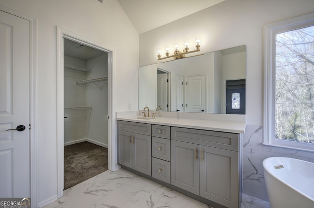 bathroom with lofted ceiling, vanity, and a bath