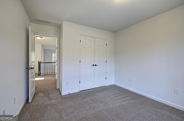 unfurnished bedroom with a closet and dark colored carpet