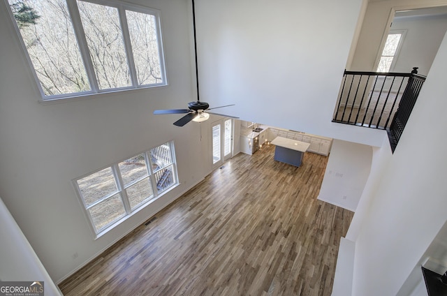 living room featuring a high ceiling, ceiling fan, a healthy amount of sunlight, and hardwood / wood-style floors