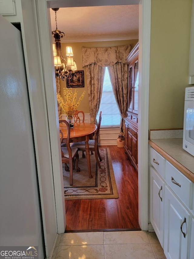 tiled dining room featuring ornamental molding and a notable chandelier