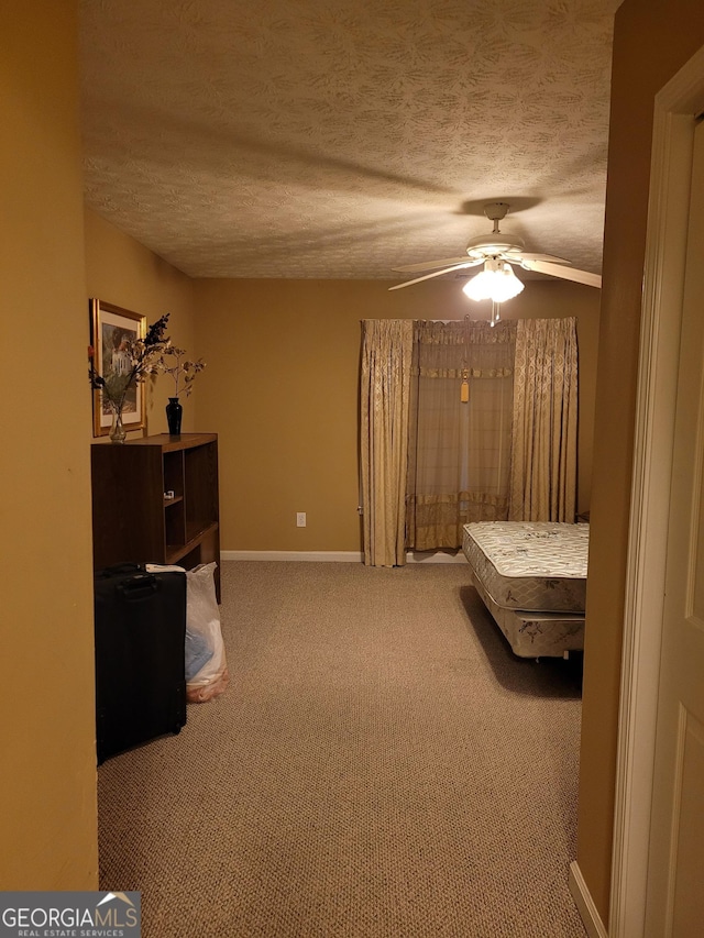 carpeted bedroom featuring ceiling fan and a textured ceiling