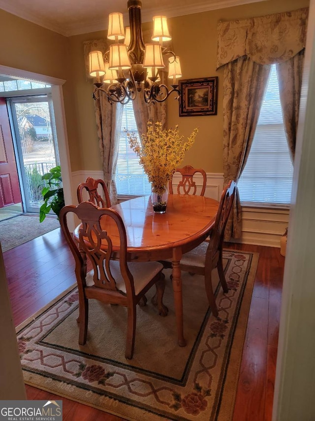 dining room with wood-type flooring, crown molding, and a notable chandelier