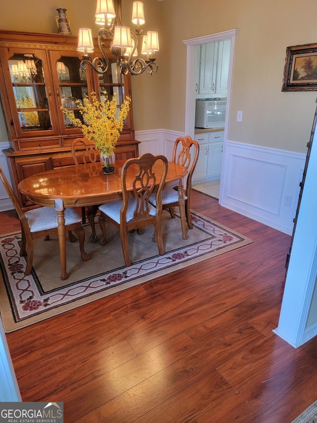 dining area with dark hardwood / wood-style floors and an inviting chandelier