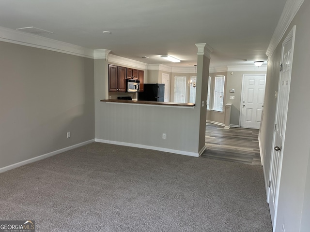 unfurnished living room with dark carpet, ornamental molding, and an inviting chandelier