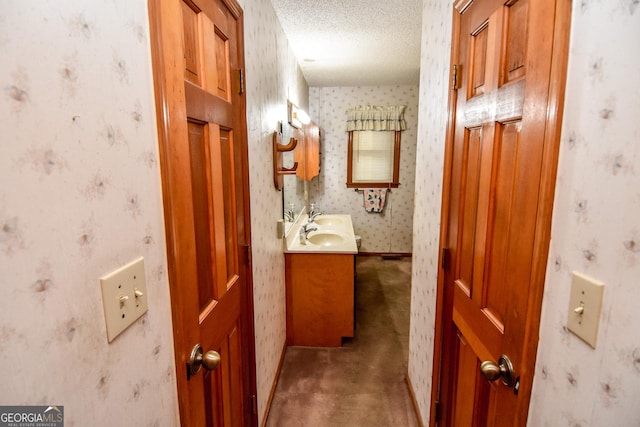 corridor with carpet floors, sink, and a textured ceiling