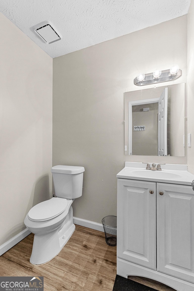 bathroom featuring a textured ceiling, vanity, hardwood / wood-style flooring, and toilet