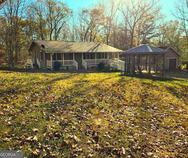 exterior space with covered porch, an outdoor structure, and a front yard