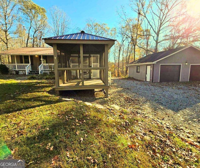 rear view of house with an outbuilding, a porch, a garage, and a lawn