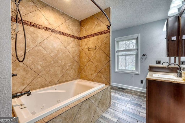 bathroom with vanity, a textured ceiling, and tiled shower / bath combo