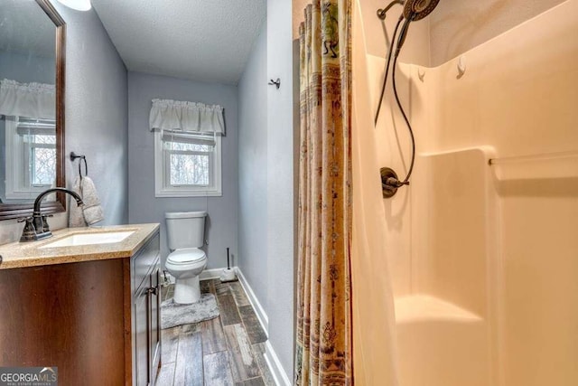 bathroom with curtained shower, wood-type flooring, a textured ceiling, toilet, and vanity