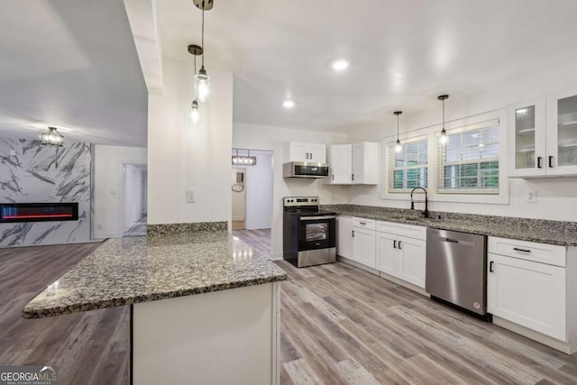 kitchen with white cabinets, stainless steel appliances, hanging light fixtures, and dark stone counters