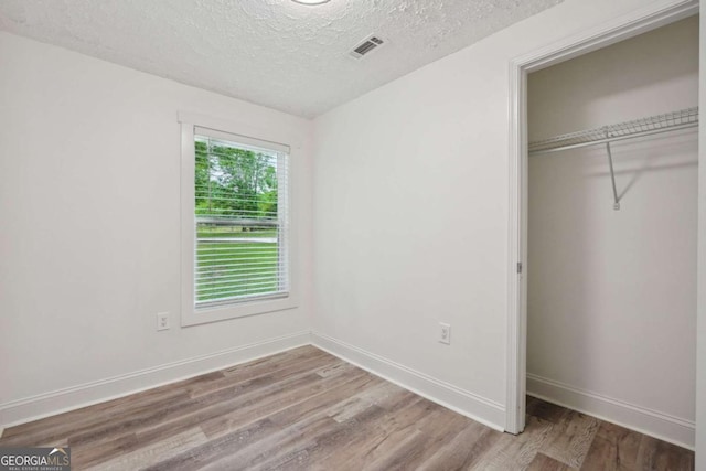 unfurnished bedroom with hardwood / wood-style floors, a textured ceiling, and a closet