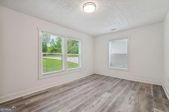 unfurnished room with hardwood / wood-style floors and a textured ceiling