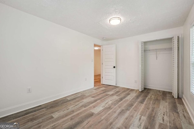 unfurnished bedroom with a closet, wood-type flooring, and a textured ceiling