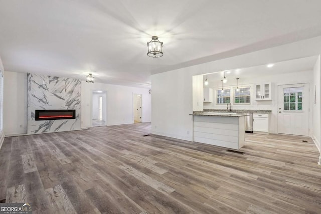 unfurnished living room with a fireplace, a chandelier, and light wood-type flooring