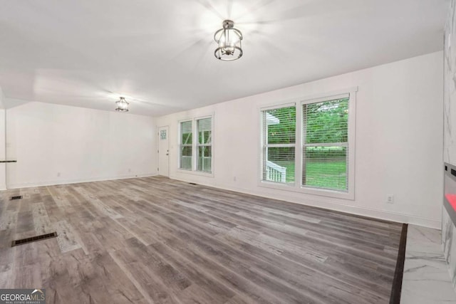 empty room with wood-type flooring and an inviting chandelier