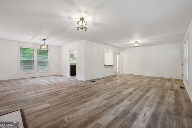 unfurnished living room with a notable chandelier and hardwood / wood-style flooring