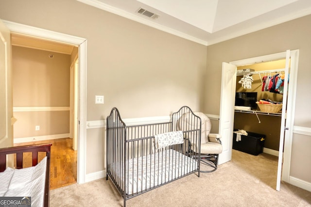 bedroom featuring vaulted ceiling, ornamental molding, a nursery area, light colored carpet, and a closet