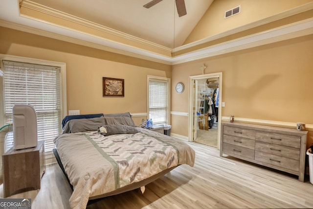 bedroom with ceiling fan, light hardwood / wood-style floors, a walk in closet, a closet, and ornamental molding