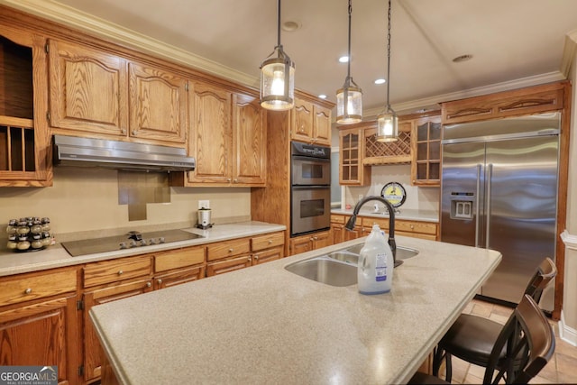 kitchen featuring double wall oven, built in fridge, sink, and an island with sink