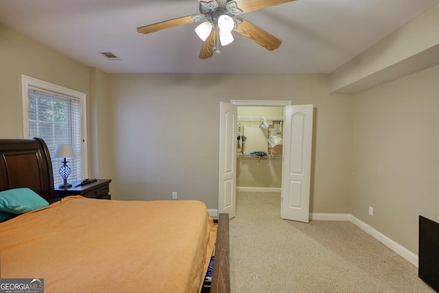 bedroom featuring carpet, a walk in closet, a closet, and ceiling fan