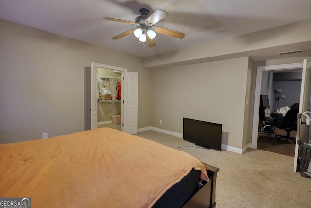 bedroom with light carpet, a walk in closet, a closet, and ceiling fan