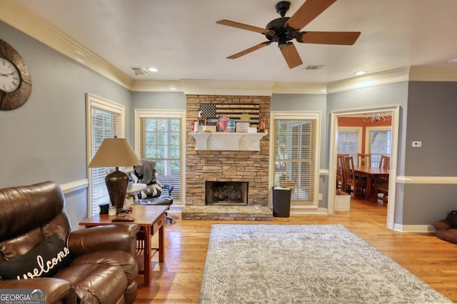 living room with light wood-type flooring, a stone fireplace, and ceiling fan