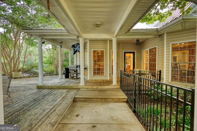 wooden deck featuring covered porch and a grill