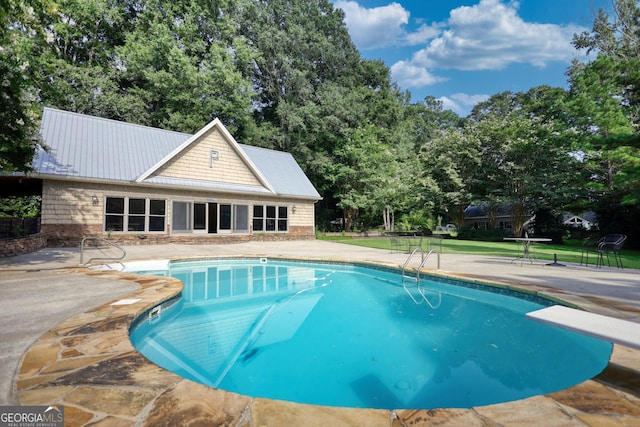 view of swimming pool featuring a patio area and a diving board