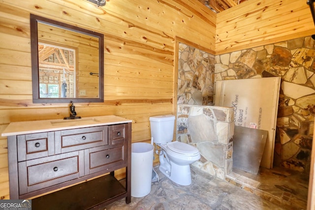 bathroom featuring vanity, wood walls, and toilet