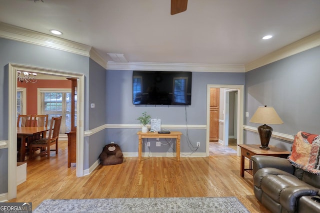 living room featuring crown molding, light hardwood / wood-style flooring, and a chandelier