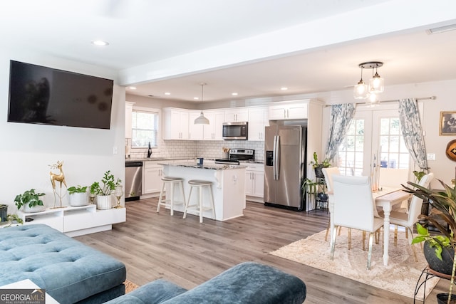 living room with light wood finished floors, recessed lighting, visible vents, and french doors