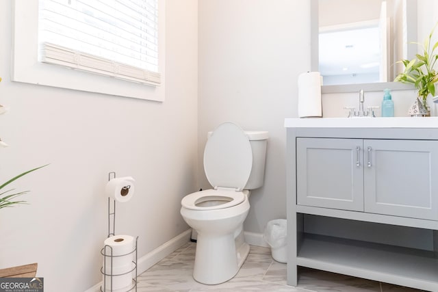 half bathroom featuring marble finish floor, vanity, toilet, and baseboards