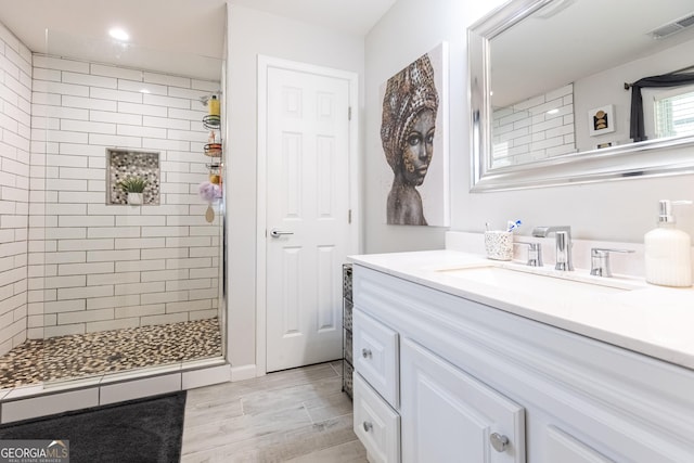 full bath with visible vents, tiled shower, and vanity